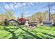 Large backyard with a built-in fire pit, grill, storage shed, mature trees, and manicured lawn at 501 Eastwood Dr, Gastonia, NC 28054