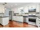 Well-lit kitchen featuring stainless steel appliances, white cabinets, mosaic backsplash, and beautiful hardwood flooring at 501 Eastwood Dr, Gastonia, NC 28054
