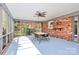 Enclosed patio with brick wall, ceiling fan, table with chairs, and view of landscaped yard at 501 Eastwood Dr, Gastonia, NC 28054