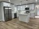 Modern kitchen featuring stainless steel appliances, an island, new white cabinets, and wood floors at 609 Mccarten St, Monroe, NC 28112