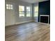 Bright living room featuring wood-look tile floors, three windows, a fireplace, and freshly painted light-gray walls at 609 Mccarten St, Monroe, NC 28112