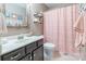 A well-decorated bathroom featuring a sink, a toilet, a shower with a pink curtain, and decorative wall hangings at 7426 Calhoun Falls Dr, Rock Hill, SC 29732