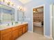 Bathroom with double sinks, wooden cabinets, and a doorway view into the main bedroom at 1021 Glen Laurel Dr, Fort Mill, SC 29707