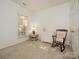 Cozy bedroom featuring neutral walls, plush carpet, and a charming rocking chair near natural light from the window at 1021 Glen Laurel Dr, Fort Mill, SC 29707