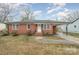Charming brick home featuring a covered parking area, landscaped front yard, and inviting front porch on a partly cloudy day at 108 White Oak St, Chester, SC 29706
