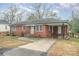 Charming brick home featuring a covered parking area and landscaped front yard on a partly cloudy day at 108 White Oak St, Chester, SC 29706