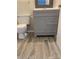 Updated bathroom with a gray vanity, toilet, wood-look tile flooring, and modern fixtures at 11022 Harrowfield Rd, Charlotte, NC 28226