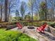 This backyard features a brick firepit surrounded by red Adirondack chairs and decorative plants at 153 Stafford Estates Dr, Salisbury, NC 28146