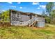Back exterior view of a grey home with a deck, stairs, and an outbuilding in a grassy yard at 1725 Bristol Rd, Statesville, NC 28677