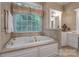 Soaking tub with a window, wallpaper, tile floors, and gold fixtures at 310 Berkeley Rd, Rock Hill, SC 29732