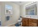 Neat bathroom with single sink, wooden cabinets, toilet, tile floor, and shower behind a curtain at 4875 Sulpher Springs Ne Rd, Hickory, NC 28601