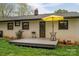 Landscaped backyard featuring a wooden patio, grill, table with umbrella, and mature trees at 706 Annieline Dr, Shelby, NC 28152