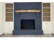 Stylish living room fireplace with painted brick, wood mantle, built-in shelving and base cabinets, and modern flooring at 923 Wyke Rd, Shelby, NC 28150