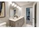 Spacious bathroom featuring double vanity with grey cabinets, large mirror with lighting, and an open doorway at 9842 Quercus Ln, Huntersville, NC 28078