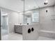 Bright bathroom featuring a glass-enclosed shower with marble tile, dual shower heads, and gray vanity with double sinks at 9934 Cask Way, Huntersville, NC 28078