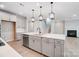 Open concept kitchen features an island with sink, gray cabinets, stainless appliances and a fireplace beyond at 9934 Cask Way, Huntersville, NC 28078