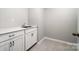Functional laundry room with gray tile flooring, crisp white cabinetry, and quartz countertops at 9934 Cask Way, Huntersville, NC 28078