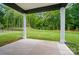 Rear covered patio featuring concrete flooring and picturesque views of the expansive green backyard and perimeter forest at 9957 Cask Way, Huntersville, NC 28078