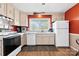 Well-lit kitchen with white appliances, tan cabinets, and a window above the sink providing a view of the outdoors at 1308 Gaston Way, Dallas, NC 28034