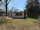 A small one-story home has light siding with blue shutters, and a brick chimney in a yard of dead grass at 1407 Birch St, Kannapolis, NC 28081
