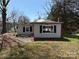 An external view of a damaged, one-story home with light siding and blue shutters needs significant repairs at 1407 Birch St, Kannapolis, NC 28081