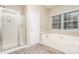 Bright bathroom featuring soaking tub and glass enclosed shower, plus tile flooring at 2514 Waters Vista Cir, Charlotte, NC 28213