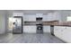 Modern kitchen featuring stainless steel appliances, granite countertops, white cabinets, and gray wood floors at 3308 Lemongrass Ln, Charlotte, NC 28214