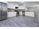 Modern kitchen featuring stainless steel appliances, granite countertops, white cabinets, and gray wood floors at 3308 Lemongrass Ln, Charlotte, NC 28214