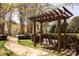 Wooden swing hangs beneath a pergola along a sidewalk near a water fountain, with green grass at 4548 Antelope Ln, Charlotte, NC 28269