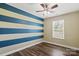 Bedroom features a striped accent wall, hardwood floors, and window at 4554 Craigmoss Ln, Charlotte, NC 28278