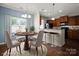 Dining area featuring a round table with seating for four, complemented by a view of the kitchen bar and natural light at 4554 Craigmoss Ln, Charlotte, NC 28278