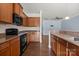 Kitchen featuring dark wood cabinets, granite countertops, black appliances, and hardwood floors at 4554 Craigmoss Ln, Charlotte, NC 28278