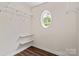 Walk-in closet with wood floors, wire shelving, and a small circular window at 4554 Craigmoss Ln, Charlotte, NC 28278