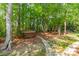 Private backyard with lush greenery and a hot tub surrounded by trees on a stone path at 4599 Rustling Woods Dr, Denver, NC 28037