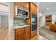 Kitchen wall featuring a stainless steel microwave and double oven, wooden cabinets and granite countertops at 4599 Rustling Woods Dr, Denver, NC 28037