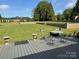 Expansive backyard featuring a well-maintained lawn, brick retaining wall, and outdoor seating area on a gray deck at 5119 Blackberry Ln, Matthews, NC 28104