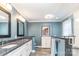 Bathroom with double sinks, white cabinets, granite counters, frameless shower, and blue accent wall at 5125 Waxwind Ln, Charlotte, NC 28226