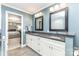 Bathroom with a granite topped vanity, large mirrors, neutral walls, and access to the primary bedroom at 5125 Waxwind Ln, Charlotte, NC 28226