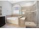 Modern bathroom showcasing a large soaking tub and a glass-enclosed shower with tiled walls at 5706 Sardis Hall Ct, Charlotte, NC 28270