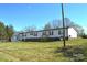 Rear view of the house showcasing the spacious yard, stairs to the back door, and additional storage buildings at 648 Dobson Farm Rd, Statesville, NC 28625