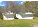 Two white outbuildings with garage doors and black roofs, set in a grassy yard with surrounding trees at 648 Dobson Farm Rd, Statesville, NC 28625
