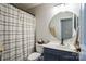 Bathroom with navy vanity, round mirror, and shower/tub combo with striped curtain at 7215 Meyer Rd, Fort Mill, SC 29715