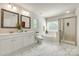 Bathroom with white marble floors, double sinks, white cabinets, a soaking tub, and walk-in shower at 722 Sandy Green Ct, Fort Mill, SC 29715