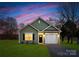 Charming single-story home with a well-maintained lawn, garage, and inviting facade set against a colorful sky at 1026 Dooley Dr, Charlotte, NC 28227