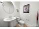 Clean powder room featuring a pedestal sink, toilet, and stylish wall decor at 10914 Zac Hill Rd, Davidson, NC 28036