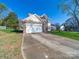 Two-story home with brick accents, blue shutters, attached garage, and a spacious driveway at 14802 Rolling Sky Dr, Charlotte, NC 28273