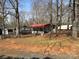 Exterior shot of the home featuring a red awning, boats, and gravel parking surrounded by mature trees at 149 Deer Park Rd # D26/27, Mount Gilead, NC 27306