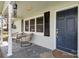Comfortable wicker chairs decorate the home's cozy front porch sitting area with printed outdoor rug at 217 Cedarhurst Ln, Clover, SC 29710