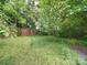 Lush backyard featuring vibrant greenery, mature trees, and a charming red brick privacy fence at 2300 Kennesaw Dr, Charlotte, NC 28216