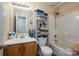 Inviting bathroom with wood vanity, large mirror, tiled floor, and shower-tub combination with storage at 2401 Gelsinger Ave, Bessemer City, NC 28016